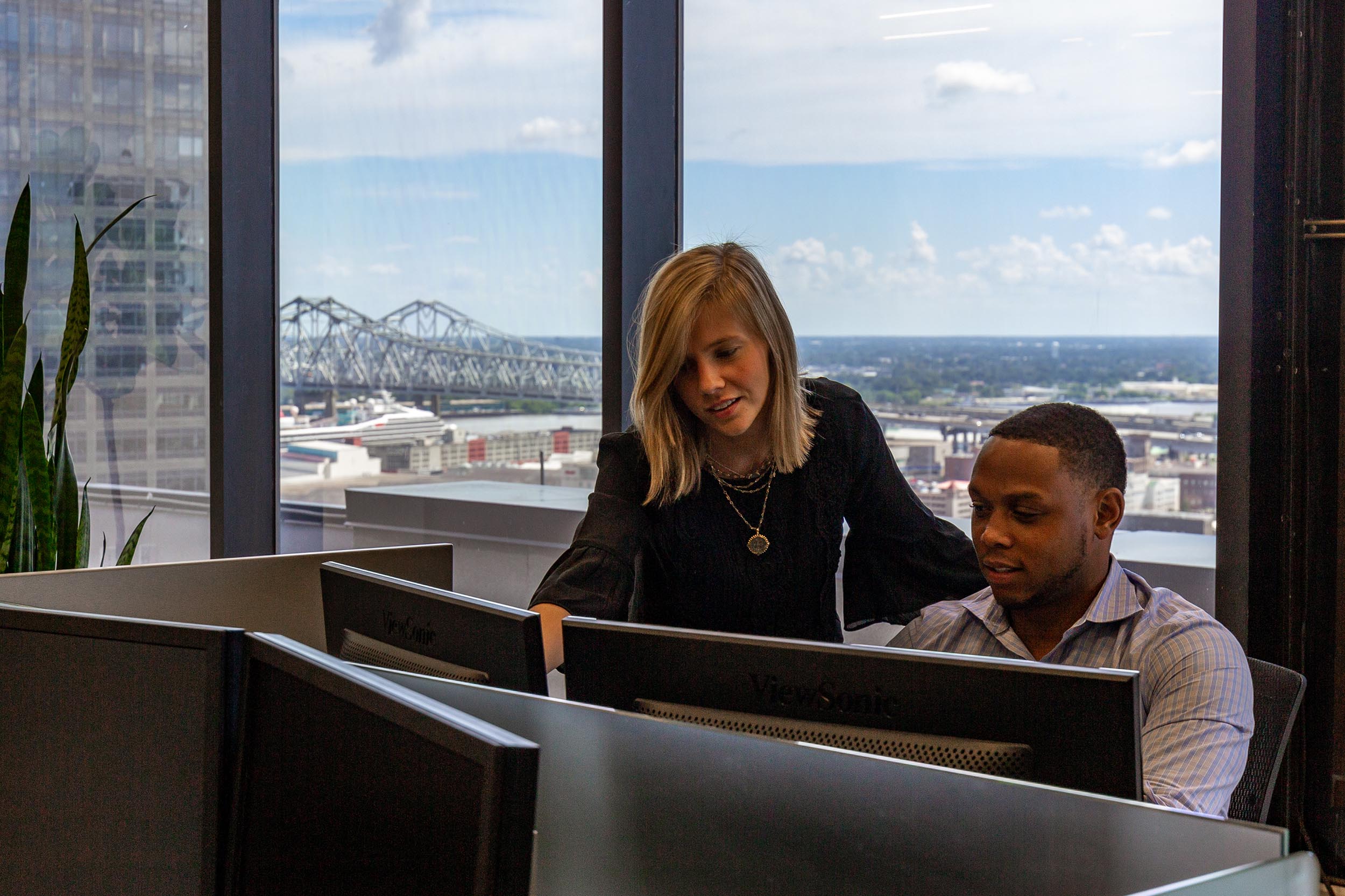 Two workers collaborate on business reports in an office overlooking downtown