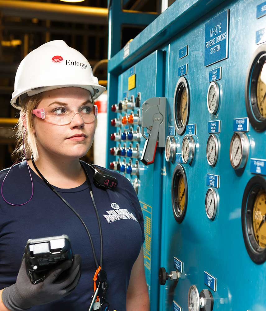 A young female worker studies dials at Entergy
