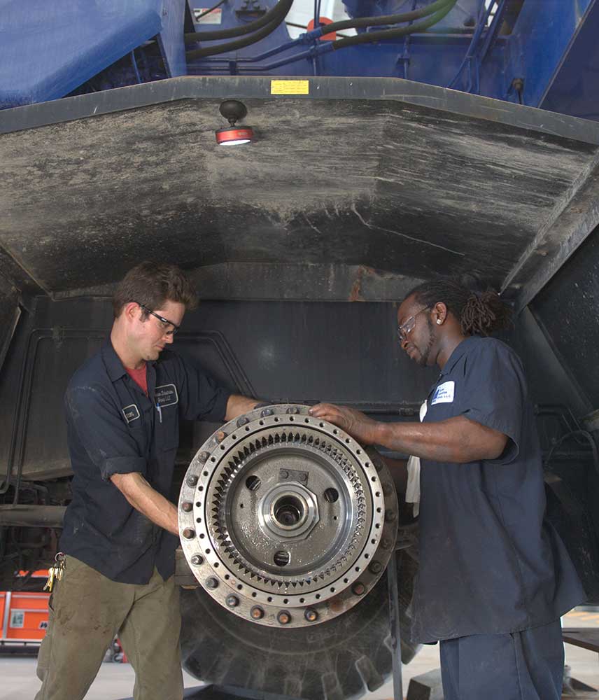 Two Turner Industries employees work together to install manufactured parts on machinery