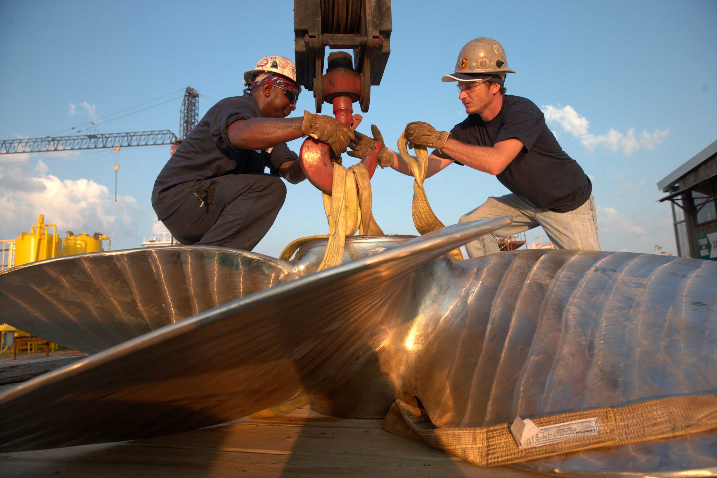 Two Bollinger workers team up to attach a large propeller to a crane to be moved